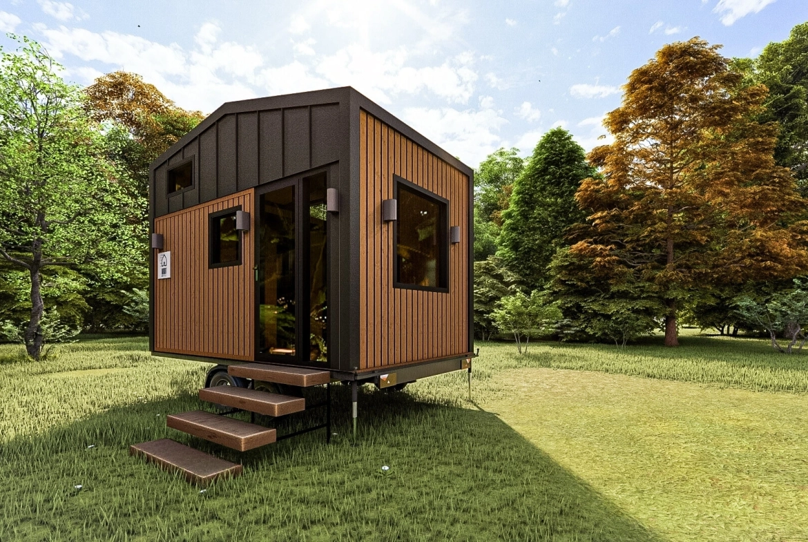 Siyah metal çatı ve ahşap dış cepheye sahip tiny house, orman manzarası eşliğinde yandan öne doğru açılı görünüm.