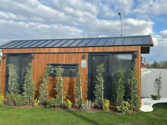 Bahçede konumlandırılmış ahşap kaplamalı modern tiny house – galvaniz çelik karkas, tam izolasyon ve geniş cam cephe tasarımıyla 4 mevsim kullanım için ideal.