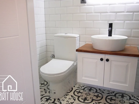 Görüntüde kompakt bir banyo alanı bulunuyor.Klozet, banyo dolabı, lavabo ve armatür bulunuyor.