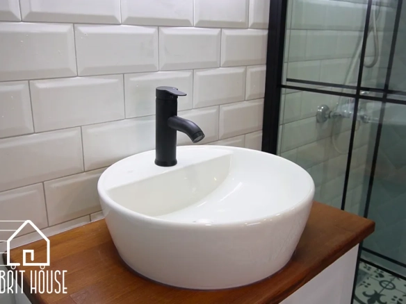 Küçük bir alanda seramik lavabo, armatür ve masif ahşap dolap detayı bulunuyor