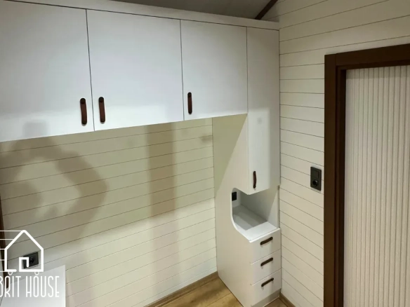 Tiny house özel tasarım yatak odası dolapları bulunuyor.Arkasında mdf beyaz paneller bulunuyor.